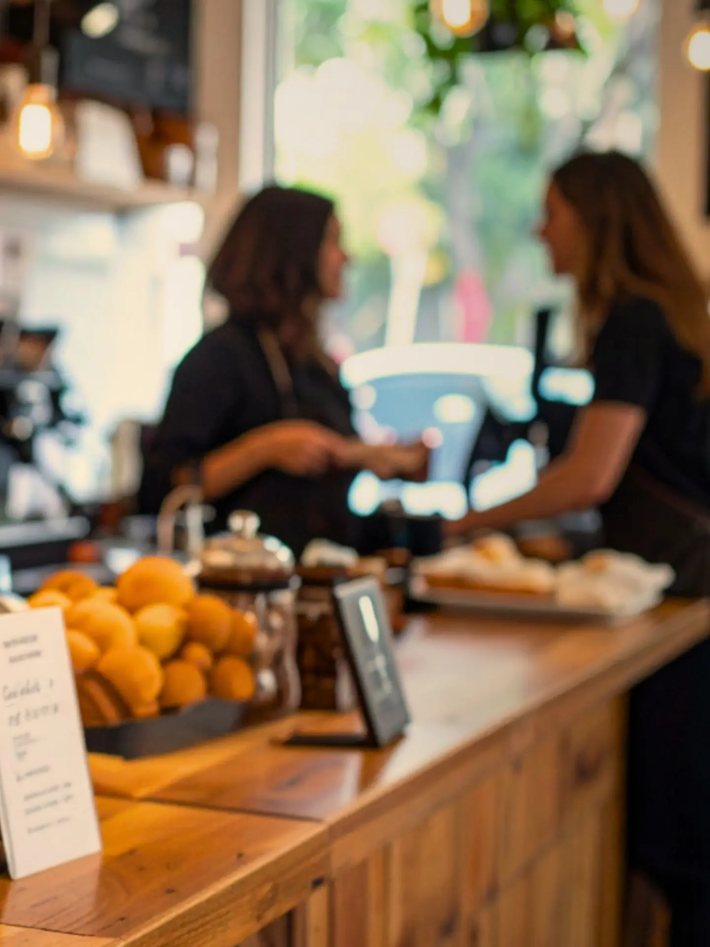 Two people talking at a warm bakery counter with pastries in the foreground